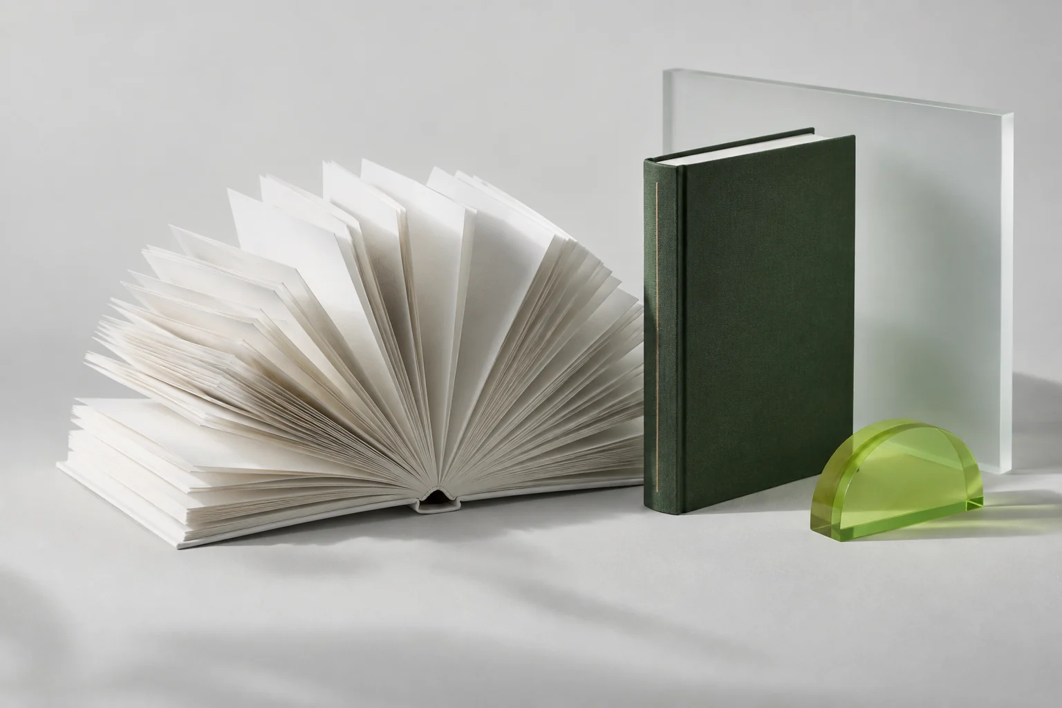 Fine paper pages, a green hardcover and considered materials in an editorial still life